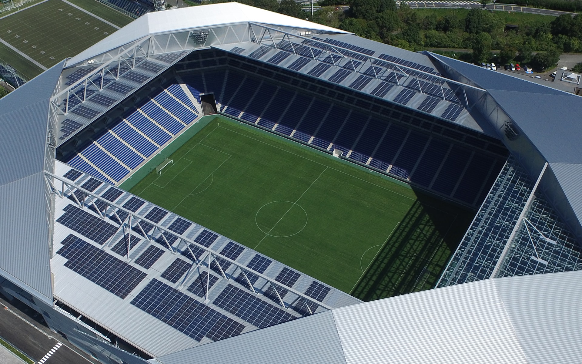 屋根3面には太陽光発電パネルを搭載、南側の一面は天然芝の育成を考慮し日光を通す素材に